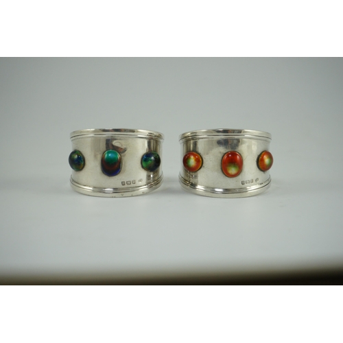 358 - Two similar Edwardian Arts & Crafts silver and enamelled napkin rings, each set with three cabochon ... 