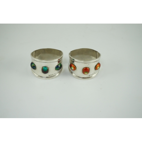 358 - Two similar Edwardian Arts & Crafts silver and enamelled napkin rings, each set with three cabochon ... 