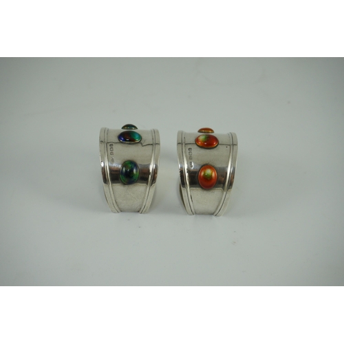 358 - Two similar Edwardian Arts & Crafts silver and enamelled napkin rings, each set with three cabochon ... 