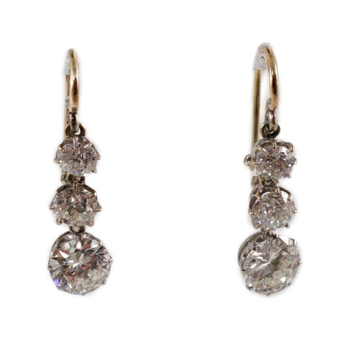 422 - A pair of early to mid 20th century gold, platinum and graduated three stone diamond set drop earrin... 