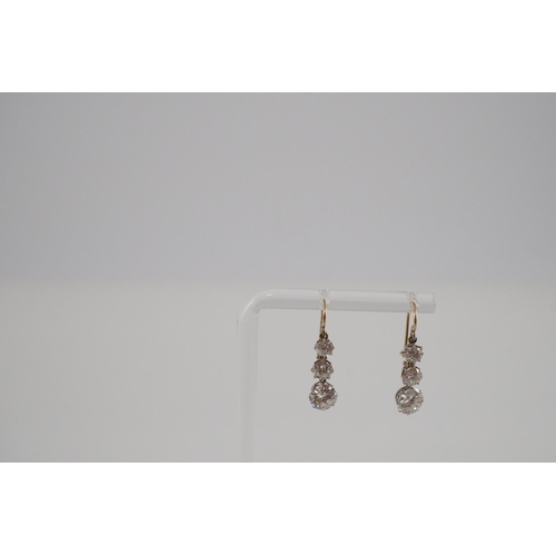 422 - A pair of early to mid 20th century gold, platinum and graduated three stone diamond set drop earrin... 