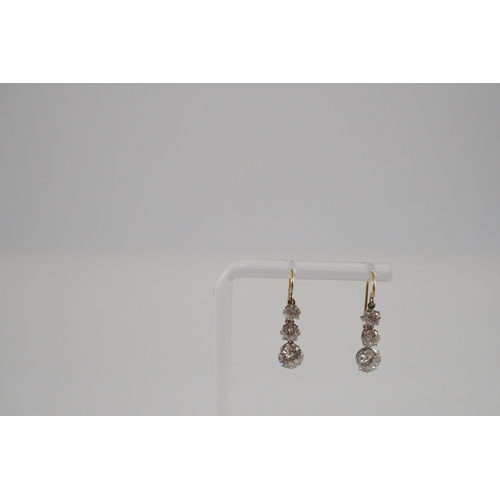 422 - A pair of early to mid 20th century gold, platinum and graduated three stone diamond set drop earrin... 