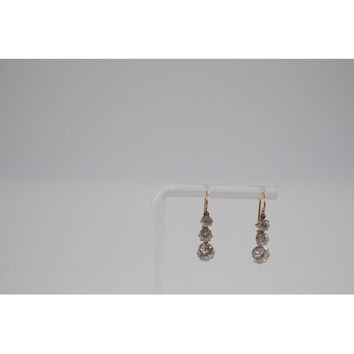 422 - A pair of early to mid 20th century gold, platinum and graduated three stone diamond set drop earrin... 