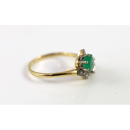 434 - A gold, emerald and diamond set two stone cross-over ring, with diamond set shoulders, the diamond a... 