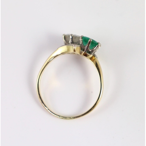 434 - A gold, emerald and diamond set two stone cross-over ring, with diamond set shoulders, the diamond a... 