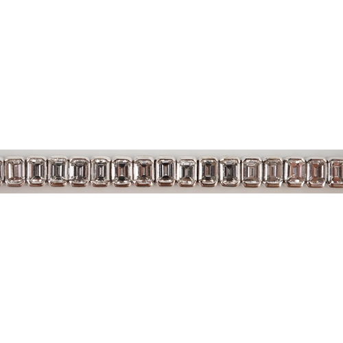 436 - A modern 18ct white gold and emerald cut diamond set line bracelet, the sixty nine stones with a tot... 