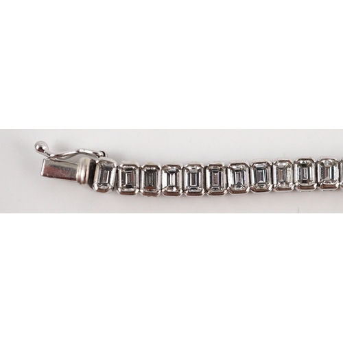 436 - A modern 18ct white gold and emerald cut diamond set line bracelet, the sixty nine stones with a tot... 