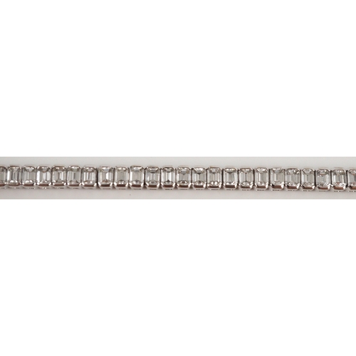 436 - A modern 18ct white gold and emerald cut diamond set line bracelet, the sixty nine stones with a tot... 