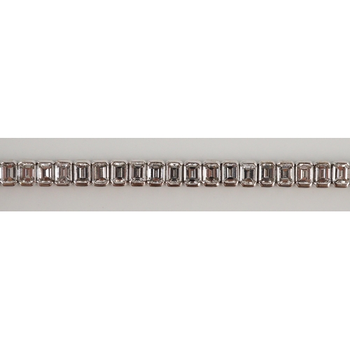 436 - A modern 18ct white gold and emerald cut diamond set line bracelet, the sixty nine stones with a tot... 