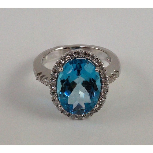 447 - A modern 18k white gold, blue topaz and diamond  oval cluster dress ring, with diamond set shoulders... 