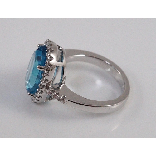 447 - A modern 18k white gold, blue topaz and diamond  oval cluster dress ring, with diamond set shoulders... 