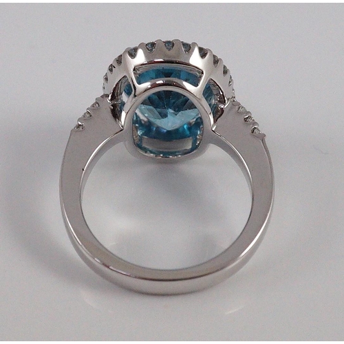 447 - A modern 18k white gold, blue topaz and diamond  oval cluster dress ring, with diamond set shoulders... 