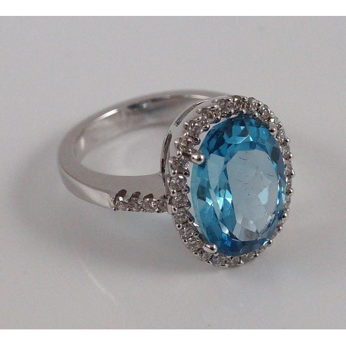 447 - A modern 18k white gold, blue topaz and diamond  oval cluster dress ring, with diamond set shoulders... 