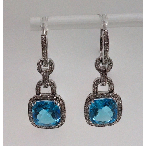 449 - A modern pair of 14kt white gold, blue topaz and diamond chip set drop earrings, each topaz weighing... 