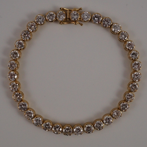 470 - A modern 18k gold and round brilliant cut diamond set line bracelet, set with thirty five stones, ea... 