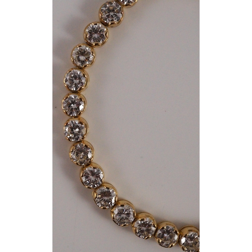 470 - A modern 18k gold and round brilliant cut diamond set line bracelet, set with thirty five stones, ea... 