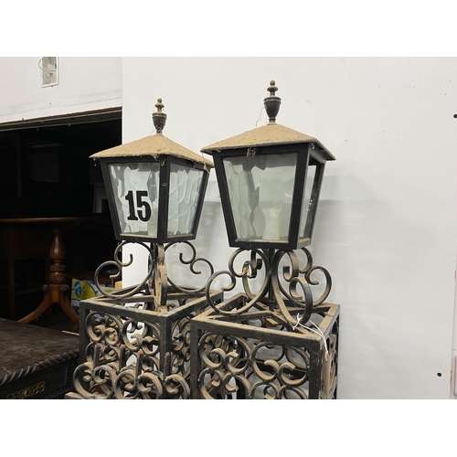 12 - A pair of black painted wrought iron scroll work gates with matching lantern posts, total width 286c... 