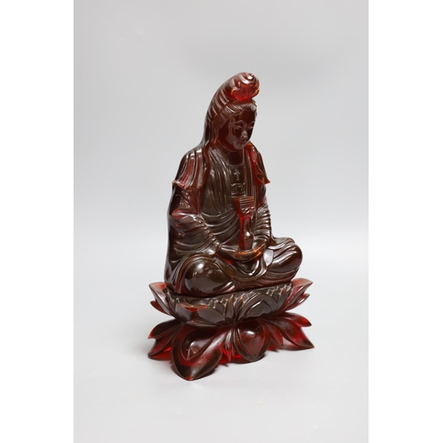 385 - A Chinese cherry amber phenolic seated figure of Guanyin, 29cms high,