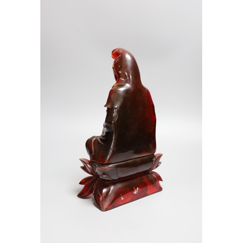 385 - A Chinese cherry amber phenolic seated figure of Guanyin, 29cms high,