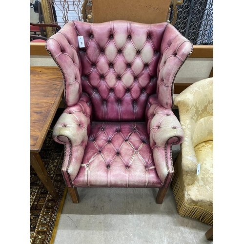 54 - A George III style button back wing armchair upholstered in faded burgundy buttoned leather, width 8... 