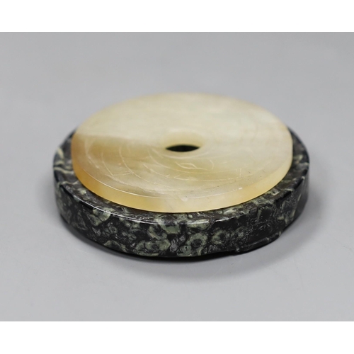 548 - Two Chinese bi discs; in bowenite jade and black and green hardstone, largest 7cm diameter