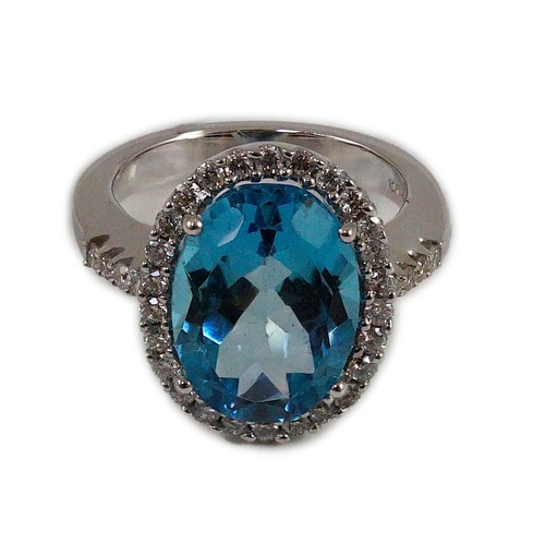 876 - A modern 18k white gold, blue topaz and diamond  oval cluster dress ring, with diamond set shoulders... 