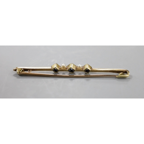 902 - An Edwardian 15ct, three stone sapphire and two stone seed pearl set bar brooch, 57mm, gross 3.4 gra... 