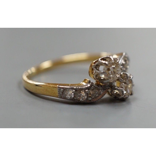 1932 - A yellow metal and two stone diamond set crossover ring, with diamond set shoulders, size J, gross w... 