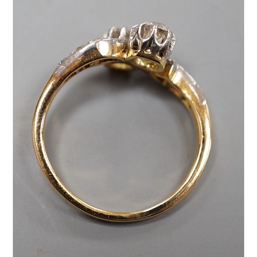 1932 - A yellow metal and two stone diamond set crossover ring, with diamond set shoulders, size J, gross w... 