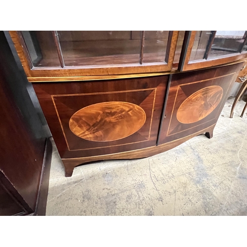 1010 - An early 20th century George III style satinwood banded mahogany inlaid bow front display cabinet, w... 