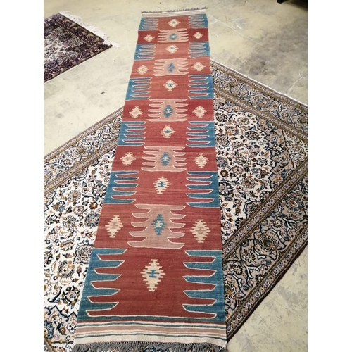 1013 - A Kilim runner with geometric motifs on a brick red ground, 384 x 85cm