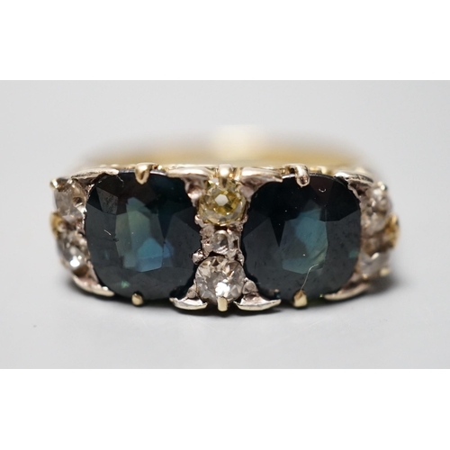 933 - A yellow metal and two stone oval cut blue/green sapphire and seven stone diamond chip set half hoop... 