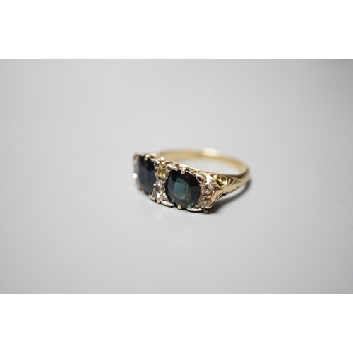 933 - A yellow metal and two stone oval cut blue/green sapphire and seven stone diamond chip set half hoop... 