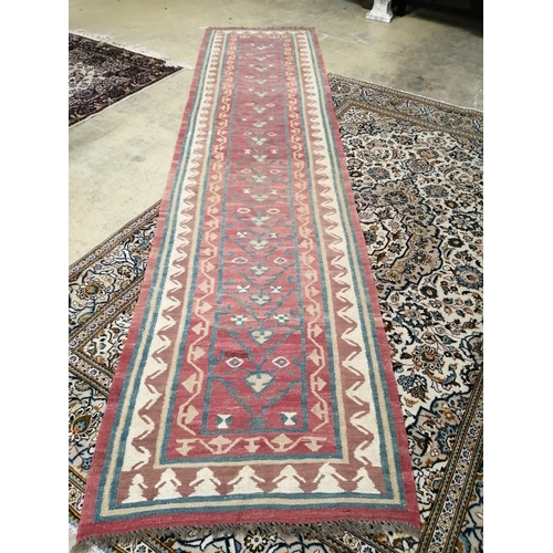 1016 - A Kilim runner with geometric motifs on a red ground, 394 x 96cm