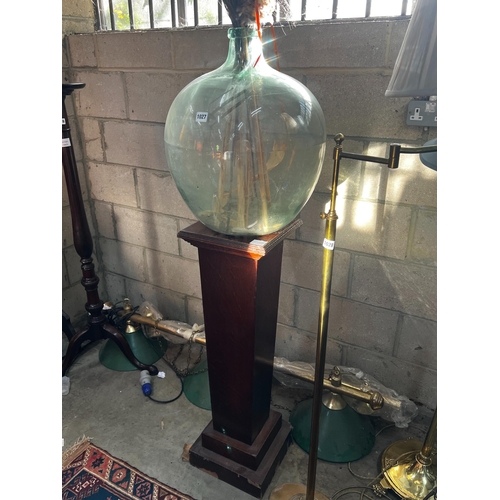 1027 - An early 20th century oak pedestal and a green glass carboy, combined height 150cm