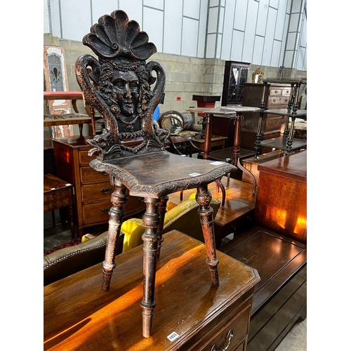 1032 - A 19th century Tyrolean oak hall chair, the back carved with a mask, a shell and serpents, height 94... 