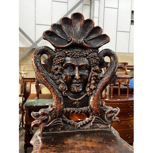 1032 - A 19th century Tyrolean oak hall chair, the back carved with a mask, a shell and serpents, height 94... 