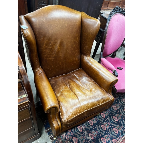 1053 - A Victorian style tan leather upholstered wingback armchair, width 78cm, depth 84cm, height 100cm... 