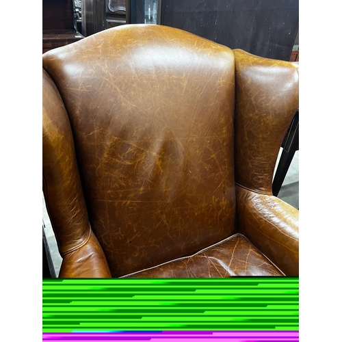 1053 - A Victorian style tan leather upholstered wingback armchair, width 78cm, depth 84cm, height 100cm... 