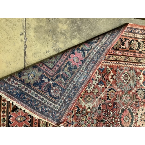 1046 - An early 20th century Heriz brick red ground carpet (worn), 418 x 330cm