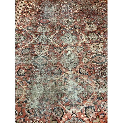 1046 - An early 20th century Heriz brick red ground carpet (worn), 418 x 330cm