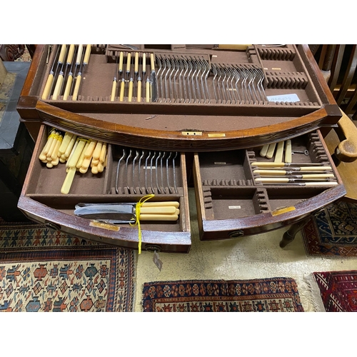 1100 - An early 20th century matched silver plated part canteen, in mahogany bow front four drawer table ca... 