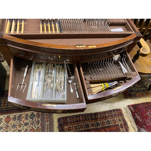 1100 - An early 20th century matched silver plated part canteen, in mahogany bow front four drawer table ca... 