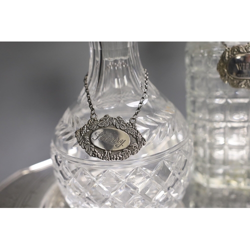 1320 - A silver plated oval tray, five assorted cut glass decanters and five assorted silver wine labels.... 