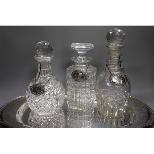 1320 - A silver plated oval tray, five assorted cut glass decanters and five assorted silver wine labels.... 