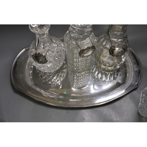 1320 - A silver plated oval tray, five assorted cut glass decanters and five assorted silver wine labels.... 