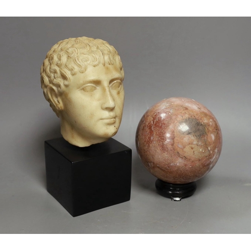 1424 - A simulated marble Roman head ornament, 24 cm and a rouge marble ball on stand, 15 cm