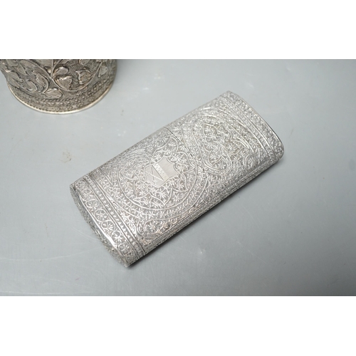 1803 - An Indian embossed white metal cigar case, 12.2cm and a similar canister and cover.