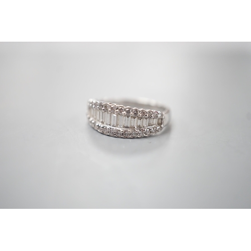 1916 - A modern white metal, graduated baguette cut diamond set half hoop ring, with diamond chip borders, ... 