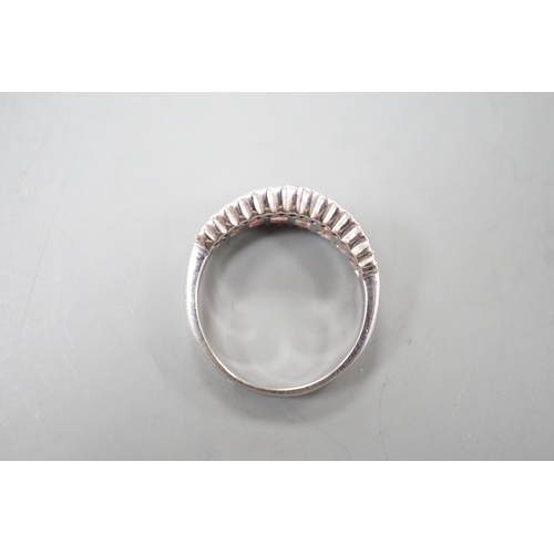 1916 - A modern white metal, graduated baguette cut diamond set half hoop ring, with diamond chip borders, ... 